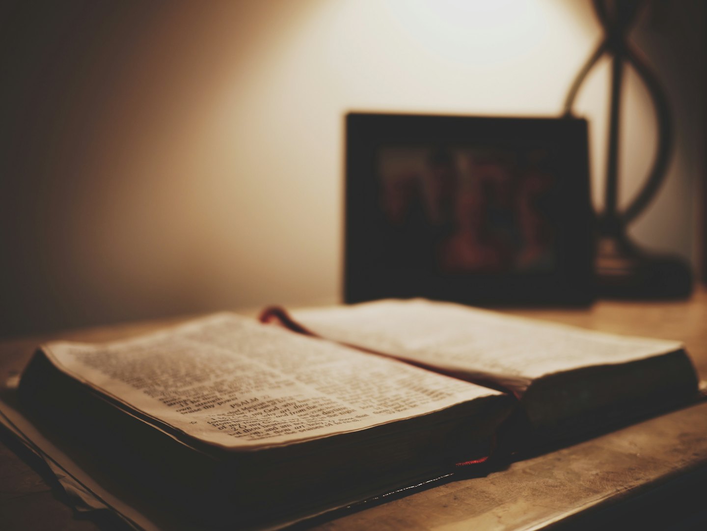 Otevřená bible na dřevěném stole s měkkým světlem.